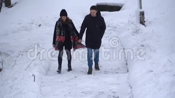 恋爱中的年轻男女在冬天的公园里散步白雪覆盖着双手冬季户外休闲快乐视频的预览图