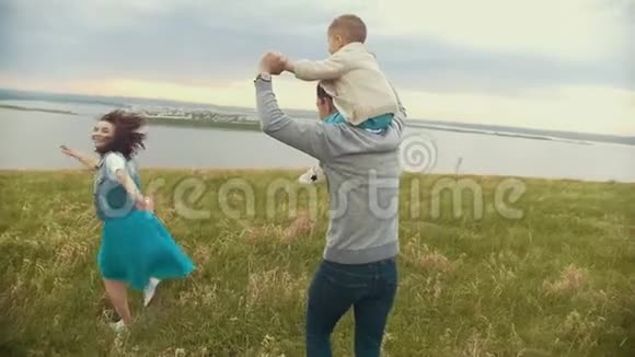 父母带着孩子在田里玩得开心父亲把儿子扛在肩上母亲吻他夏天视频的预览图