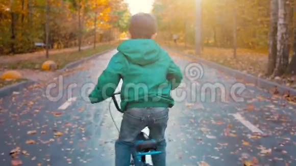 秋天小男孩在城市公园骑蓝色自行车视频的预览图