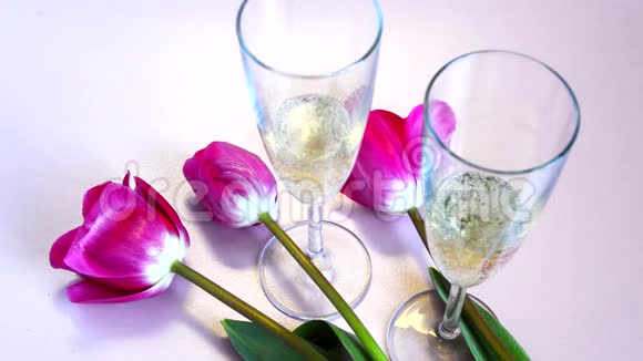 两杯起泡葡萄酒和红色郁金香气泡可见视频的预览图