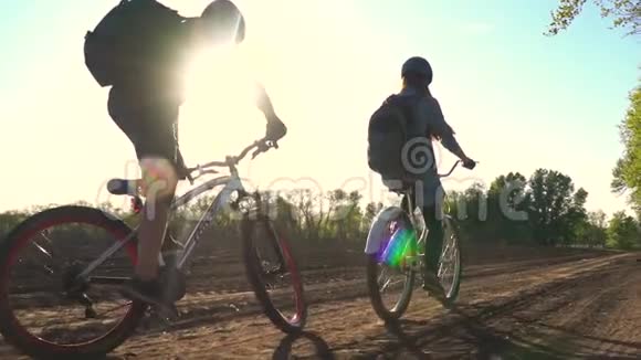 慢镜头拍摄一对骑自行车的人沿着靠近树木的土路行驶视频的预览图
