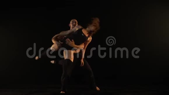 在杂技瑜伽上一个男人把一个女孩抱在怀里和她一起旋转慢动作视频的预览图
