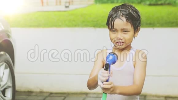 快乐的小男孩用水管玩水视频的预览图