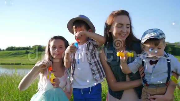 带着肥皂泡的情感家庭在河边的草地上靠着天空休息视频的预览图