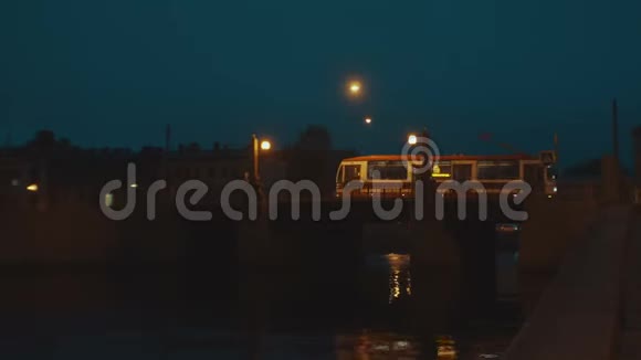 城市有轨电车夜间在旧城的桥上行驶桥上的灯是黄色的视频的预览图