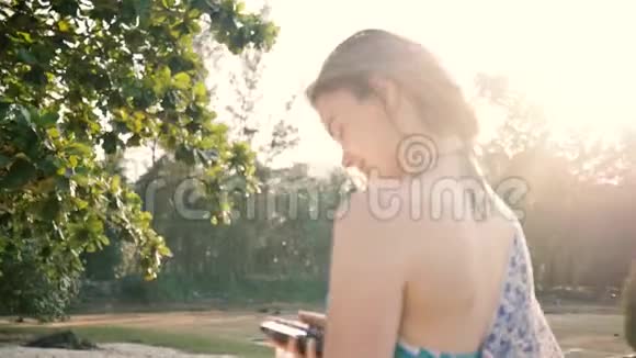 在海滩上看智能手机的红发女孩视频的预览图
