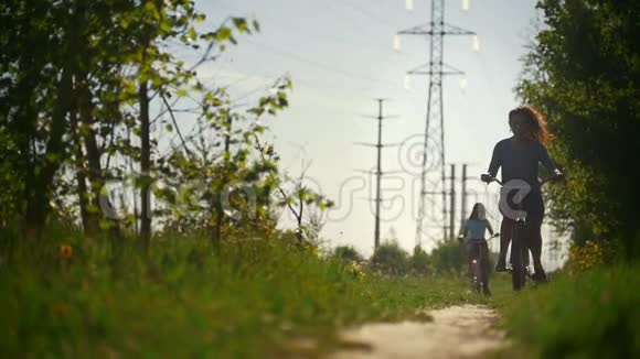 在蓝天和绿树的背景下两个深色头发的骑自行车的人顺利地沿着小路经过视频的预览图