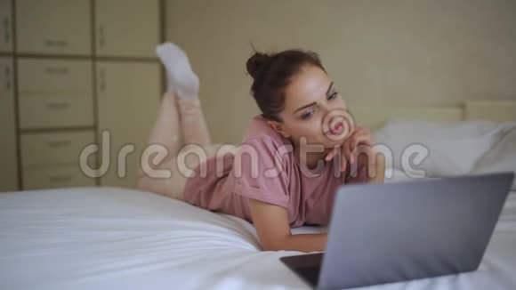 在床上笔记本电脑上看电影的女人视频的预览图