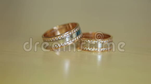 米色背景上的金色订婚戒指结婚戒指视频的预览图