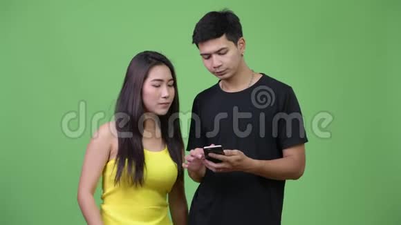 一对年轻的亚洲夫妇用电话看起来很震惊视频的预览图