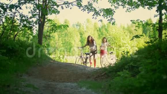在森林里骑自行车骑自行车的两个女朋友在交流中玩得很开心从空地爬到小路上视频的预览图