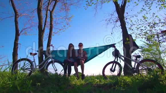 慢镜头拍摄一对爱骑自行车的人在吊床上休息视频的预览图