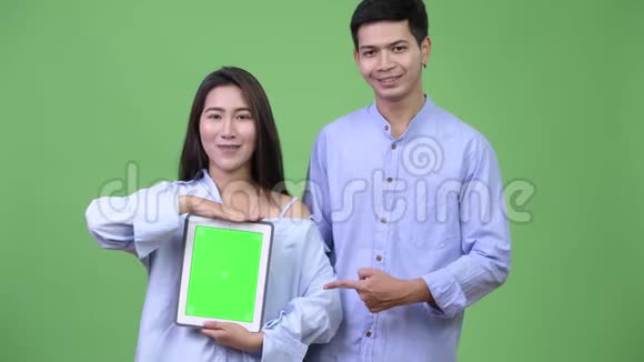 年轻快乐的亚洲商务夫妇展示数码平板电脑竖起大拇指视频的预览图