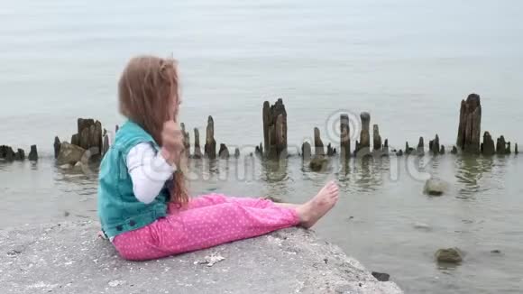 女孩坐在海边的石头上视频的预览图