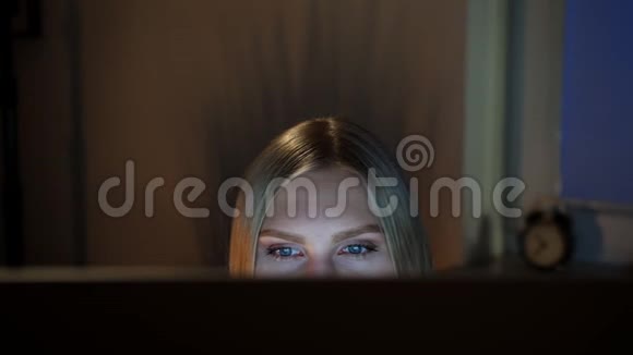 女人晚上偷看电脑显示器晚上坐在电脑前看电脑的美丽女性的作物景观视频的预览图