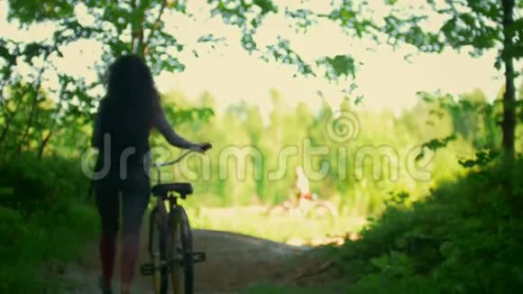 女孩骑自行车的人在森林里的空地上遇见她的朋友阳光明媚的夏日视频的预览图