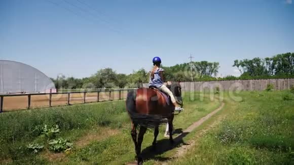 一个戴着防护头盔的少女骑着一匹棕色的马视频的预览图