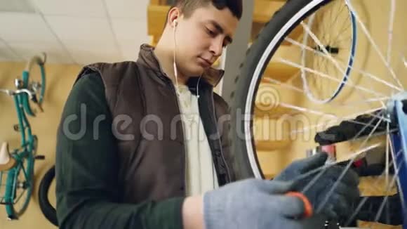 集中的机械师检查旋转自行车轮然后用特殊工具固定辐条同时维修自行车和视频的预览图