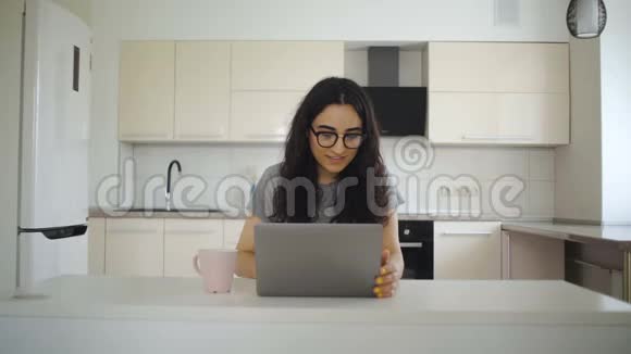 女人在厨房的餐桌上看喜剧电影视频的预览图