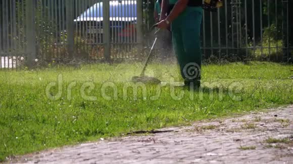 男园丁用公园里的汽油割草机割草慢动作视频的预览图