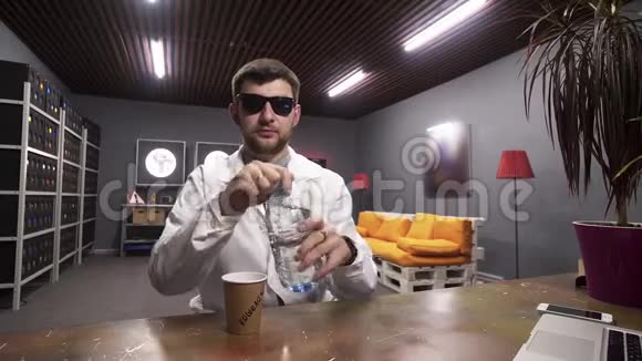 穿着白色实验外套的可爱男人把水从塑料瓶倒入纸杯视频的预览图