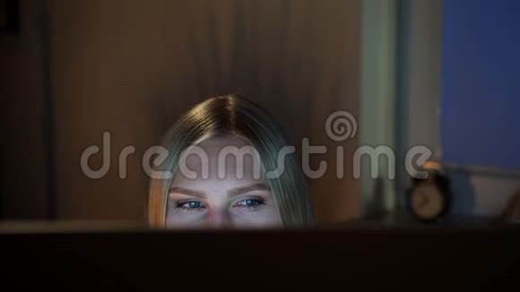 女人晚上偷看电脑显示器晚上坐在电脑前看电脑的美丽女性的作物景观视频的预览图