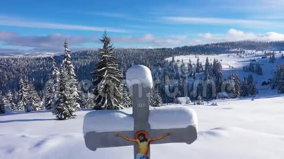空中4k无人驾驶飞机在山上看到一个白雪覆盖的宗教十字架视频的预览图
