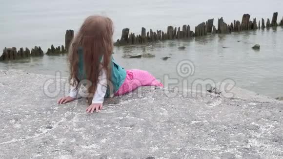 女孩坐在海边的石头上视频的预览图