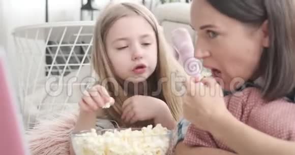 妈妈带着女儿在家吃爆米花和聊天视频的预览图