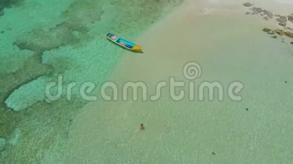 菲律宾一望无际的绿松石蔚蓝的海水和环礁中的女性和小船的鸟瞰图视频的预览图