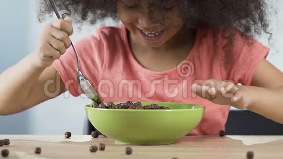 快乐的小女孩吃着美味的早餐麦片粥和巧克力泡芙视频的预览图