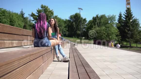 两个漂亮的女朋友在公园里坐在长凳上聊天心情很好视频的预览图
