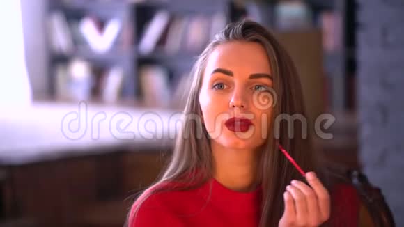 女人用唇膏涂抹嘴唇化妆应用唇彩唇膏年轻漂亮的姑娘给她涂胭脂的画像视频的预览图