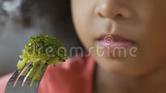 特写小孩子拿着新鲜的绿色西兰花在叉子上美味的蔬菜视频的预览图