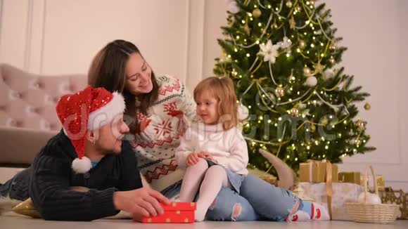 圣诞老人家躺在地板上父母和婴儿在卧室有乐趣人们在家放松冬季视频的预览图