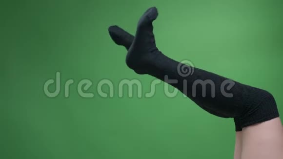 穿着可爱的黑色针织袜子的少女美腿特写镜头玩味地移动着背部被隔离在绿色上视频的预览图