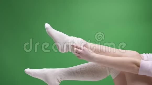 在可爱的白袜子中的少女腿的特写镜头嬉戏地移动背部孤立在绿色上女孩视频的预览图