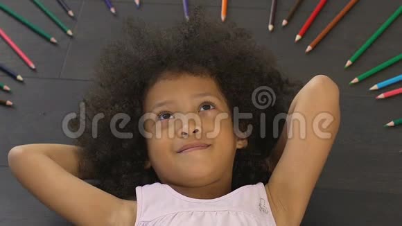 可爱的小女孩躺着双手抱在脑后真诚地微笑着视频的预览图