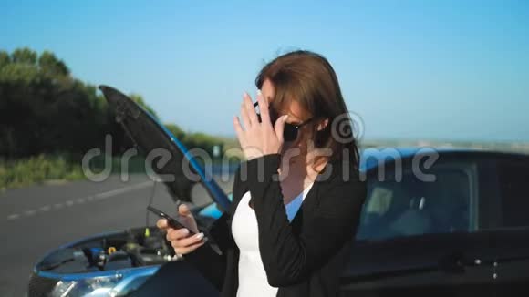 路上一辆破车附近的女人正在呼救年轻担心的女孩正在用电话解释视频的预览图