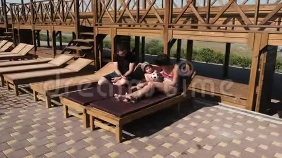 看一家人躺在游泳池前的躺椅上踢着足球视频的预览图