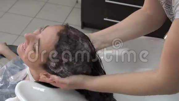 美容师发型师在美容院给一个黑发女孩洗头视频的预览图