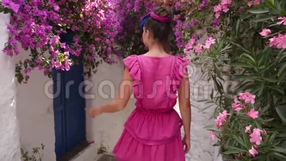 年轻女子走在白房子之间的一条狭窄的街道上视频的预览图