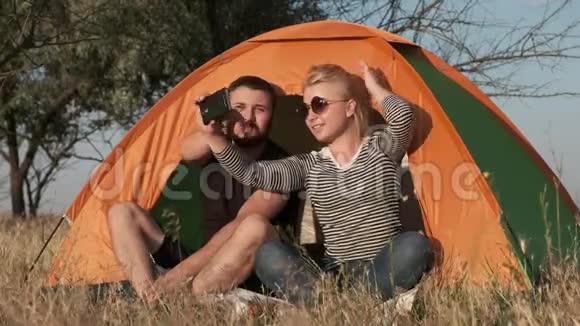 一对夫妇在帐篷里自拍而年轻的女人正在整理头发视频的预览图