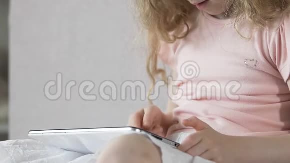 靠近坐在沙发上玩平板电脑游戏的小女人小玩意视频的预览图