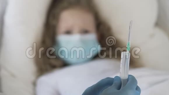 戴着医疗面具的惊恐卷发儿童看着注射器生病了视频的预览图