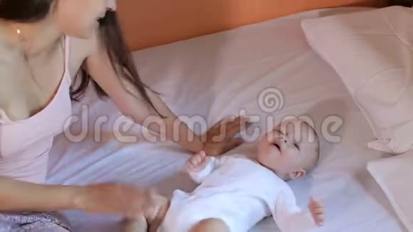 快乐的年轻妈妈在卧室的家里亲吻和拥抱她的新生儿视频的预览图