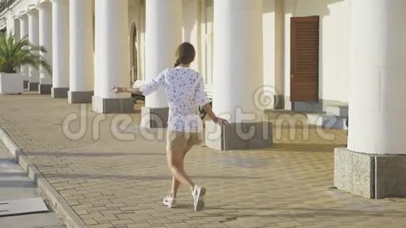 年轻漂亮的女孩在公园里跳舞那个女孩在度假小镇上跳舞跳跃稳定射击4k视频的预览图