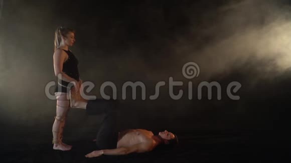 一个在什巴里的女人和一个男性裸露上身在烟雾中做杂技瑜伽慢动作视频的预览图