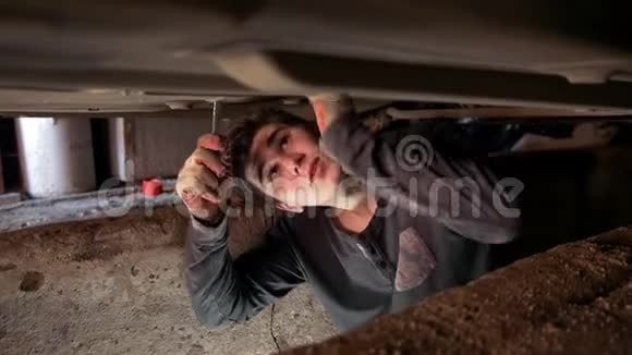 汽车底下的年轻人在车库坑里修理汽车视频的预览图