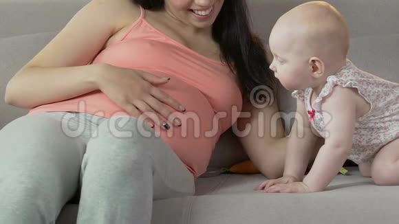 婴儿站在沙发上看着孕妇揉肚子视频的预览图